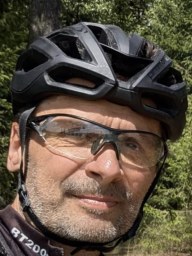 Tomáš Sedláček v cyklistické helmě a brýlích na lesní cestě